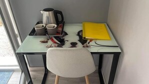 A small, modern room with a glass table, a chair, a kettle, cups, a notebook, and a dog. - La Petite Salamandre (Chitenay)