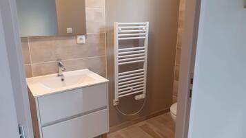 A bathroom with a white sink, a mirror, a towel rack, and a toilet.