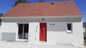 A single-story building with a red door, a small window on the right, and a chimney on the roof. - La Petite Salamandre (Chitenay)