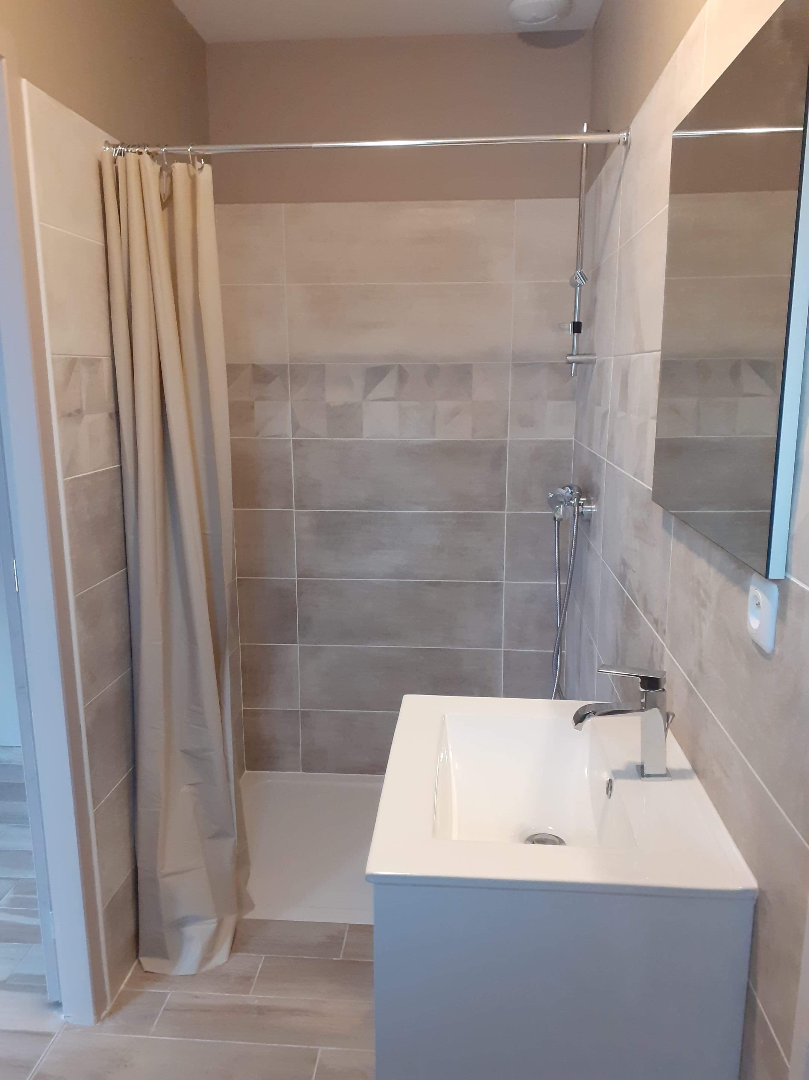 Un baño moderno con ducha, lavamanos y espejo.
