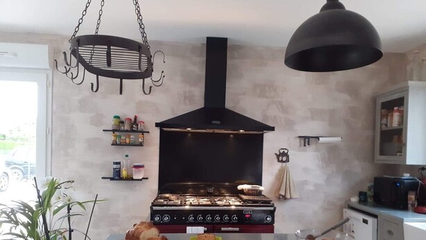 A kitchen with a gas stove, hanging light fixture, and various food items on the counter. - La Petite Salamandre (Chitenay)