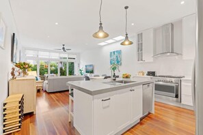 A modern kitchen with a central island, stainless steel appliances, and pendant lighting. - Bright Home in Trendy Newtown close to the Park (Newtown)
