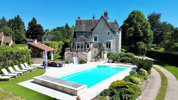 A large house with a swimming pool, a covered patio, and a well-maintained garden.
