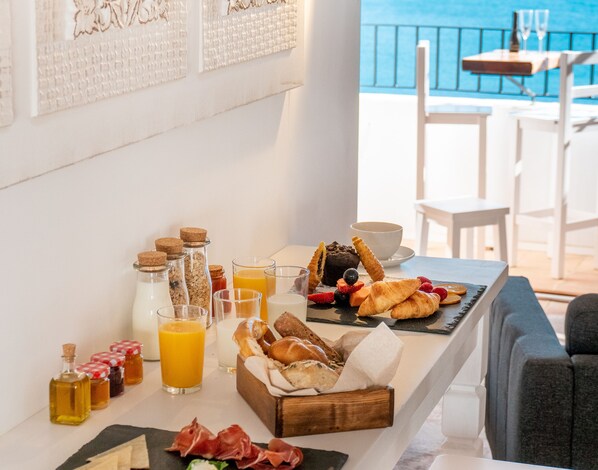 A breakfast table with various foods and drinks, a view of the sea, and a white chair. - Porta Nova Suites Altea - Adults Only (Altea)