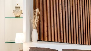 A neatly arranged hotel room with a bed, bedside tables, a tray of breakfast, and a wooden panel wall. - Porta Nova Suites Altea - Adults Only (Altea)