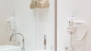 Un baño con lavamanos blanco, espejo, secador de pelo y decoración de pared de piedra.