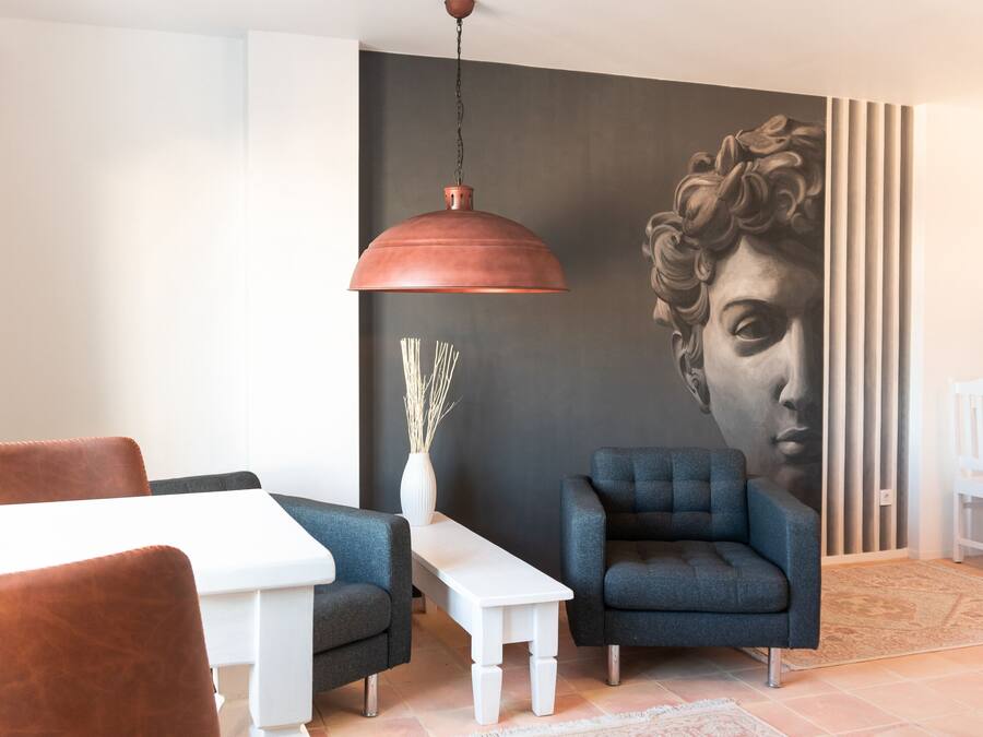 Un salon moderne avec une table blanche, un canapé bleu et une grande fresque murale.