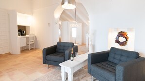 A modern living room with two grey sofas, a white coffee table with a bottle and glasses, and a pendant light. - Porta Nova Suites Altea - Adults Only (Altea)