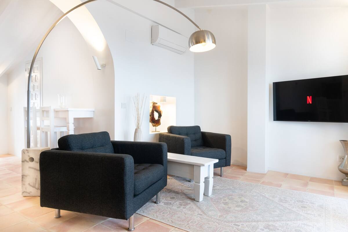 A modern living room with a curved ceiling, a flat-screen TV, and a white coffee table.