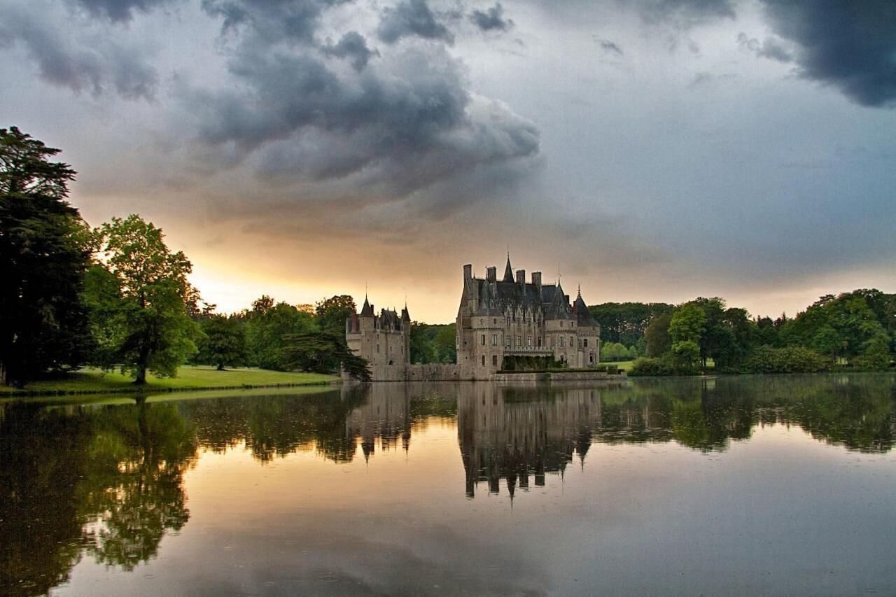 A castle with a large courtyard and a reflective lake.