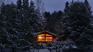 Eine Hütte mit Balkon, umgeben von schneebedeckten Bäumen.