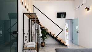 Un intérieur moderne avec un escalier, un téléviseur à écran plat et une porte vitrée donnant sur l’extérieur.