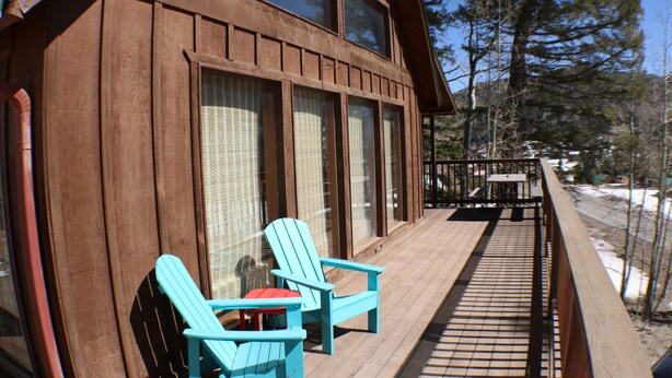 Une cabane en bois dotée d’un balcon, de deux fauteuils Adirondack et d’une table.