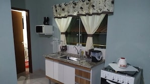 A kitchen with a granite countertop, a sink, a stove, and a microwave. - Naldo Ilha Bela (Ilhabela)