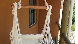 A white macrame hanging chair suspended from a wooden beam. - Naldo Ilha Bela (Ilhabela)