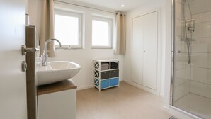 A modern bathroom with a large white sink, a glass shower enclosure, and a storage unit with multiple compartments. - Beautiful vacation apartment in Kassel (Kassel)