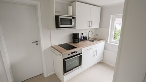 A compact kitchen with white cabinets, a microwave, a coffee maker, and a sink. - Beautiful vacation apartment in Kassel (Kassel)