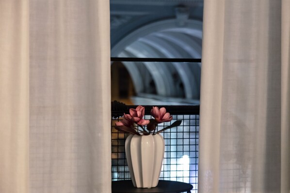 Un vase blanc orné de fleurs roses, posé sur une table noire devant un mur carrelé.