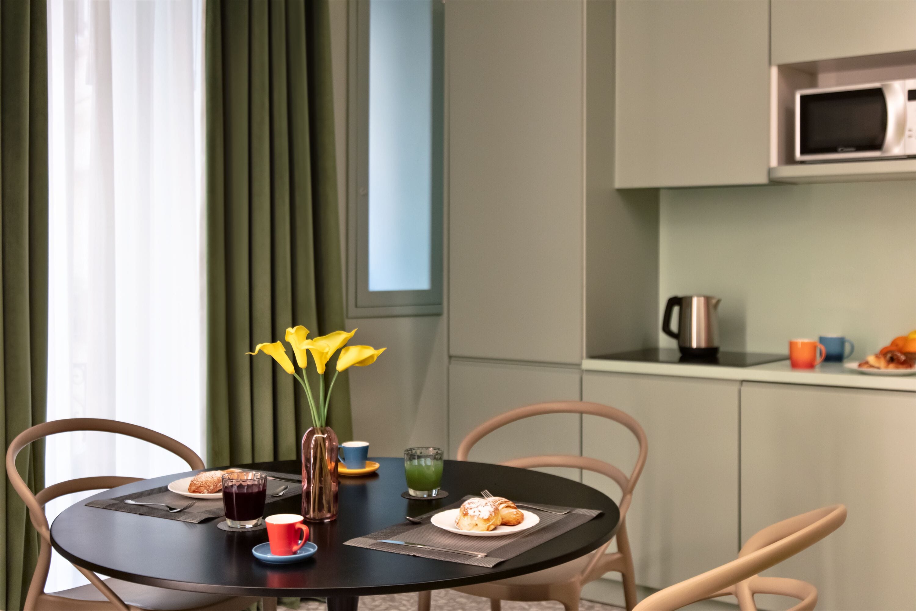 A dining table with a plate of food, a cup, and a vase with flowers.