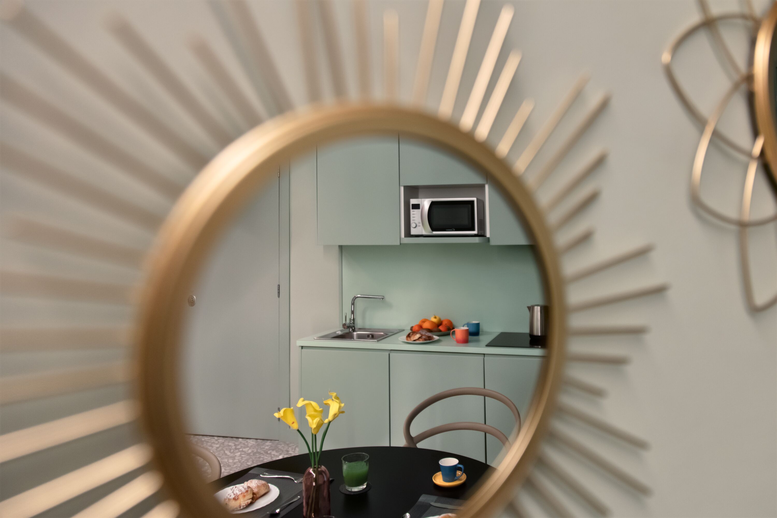 A modern kitchen with a microwave, sink, and a dining area with a table and chairs.