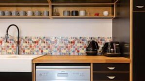 Uma cozinha moderna com lava-louças, cafeteira e painel de azulejos.