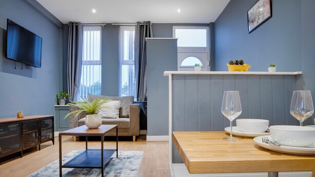 Een moderne woonkamer met een bank, salontafel en een eettafel, compleet met wijnglazen en schalen.
