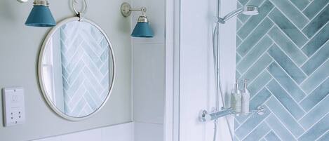 A bathroom with a white sink, a mirror with a herringbone tile backsplash, and a shower with a herringbone tile wall.