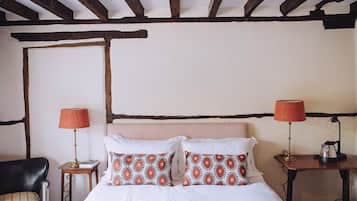A bedroom with a bed, two bedside tables, a chair, and a wooden ceiling.