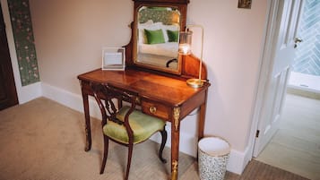 A wooden desk with a mirror, a green chair, and a floor lamp.