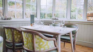 A dining area with a table set for four, surrounded by green upholstered chairs with a patterned design.