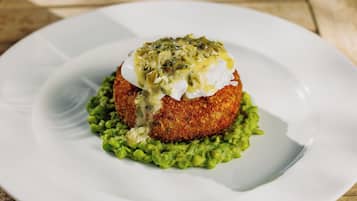 A white plate with a food item on top of a green base, possibly a dish with a creamy sauce and green topping.