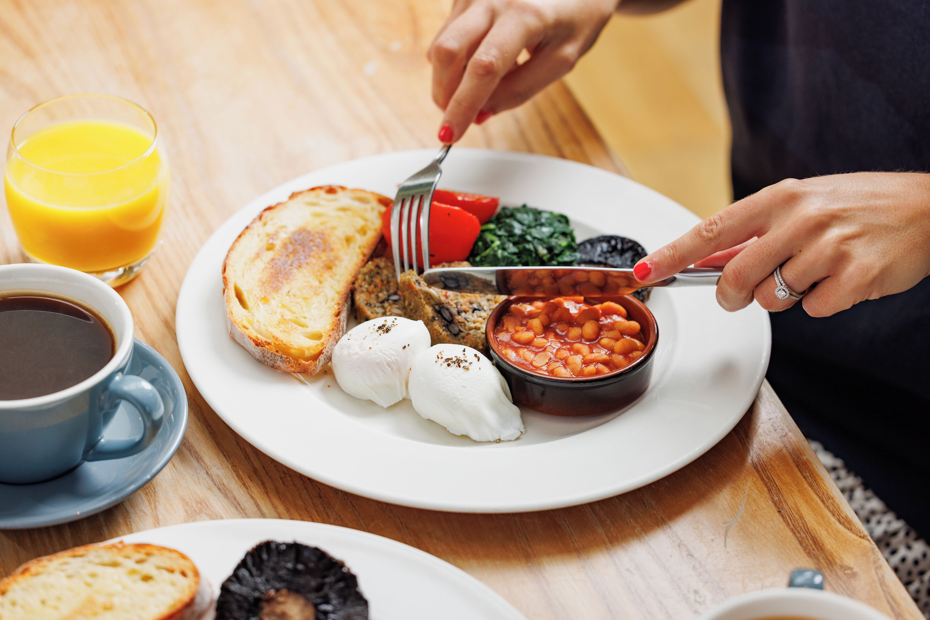 A breakfast plate with toast, eggs, beans, and a glass of orange juice.