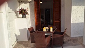 A patio with wicker furniture and a table set with yellow containers. - Villetta Lorena 100mt from the sea, Salento  (Marina di Mancaversa)
