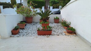 A rooftop garden with potted plants arranged in a row, surrounded by white walls and a gravel path. - Villetta Lorena 100mt from the sea, Salento  (Marina di Mancaversa)