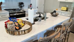 A kitchen with a central island, a sink, and bar stools.