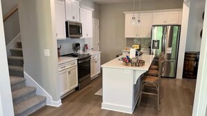 A modern kitchen with white cabinetry, stainless steel appliances, and a central island.