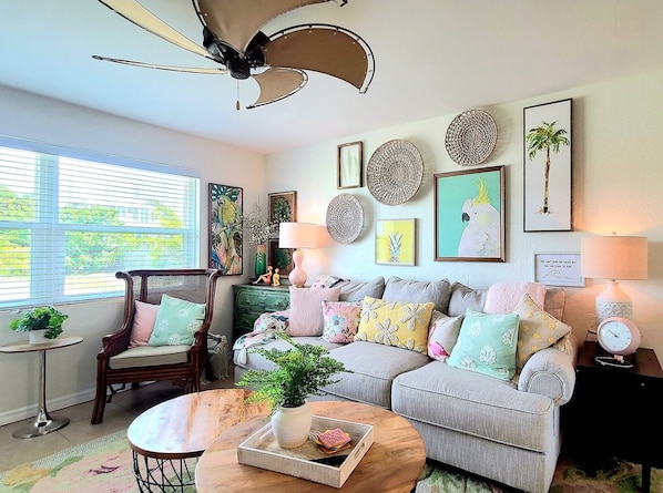 A cozy living room with a sofa, a chair, a coffee table, and a ceiling fan.