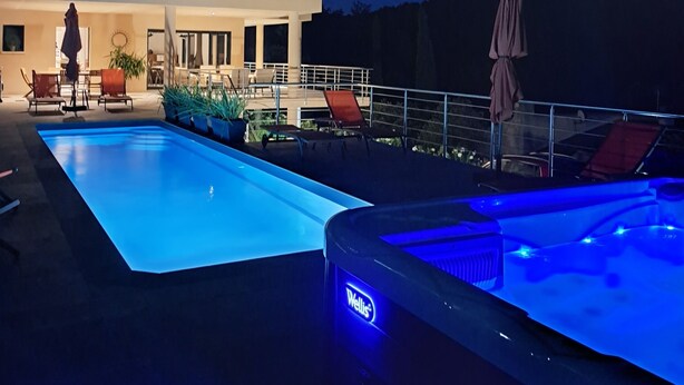 Une piscine avec un jacuzzi et des chaises longues.