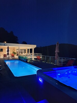 Una piscina con jacuzzi y sillones de descanso.