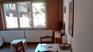 A dining area with a table, chairs, a radiator, and a window with a view of buildings outside.