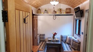 A cozy kitchen with wooden cabinets, a central island, and a hanging light fixture. - Luxury romantic shepherd's hut - hot tub and Aga  (Camelford)