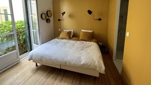 Een slaapkamer met een groot bed, een schuifpui naar een balkon en een wandlamp.
