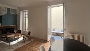 Een ruime woonkamer met een houten vloer, een zwarte eettafel en een zithoek.