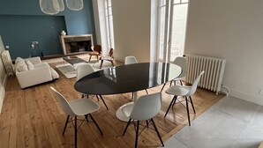 Een moderne woonkamer met een ronde eettafel, witte stoelen, een bank en een open haard.