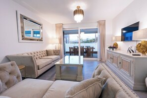 Un salon avec un canapé, une table basse et un téléviseur. Il y a un balcon avec vue.