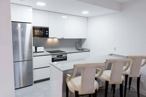A modern kitchen with white cabinetry, stainless steel appliances, and a central island with chairs. - Cala Serena, Elegant 2 bedroom apartment only 850 m from the beach in La Cala de (La Cala de Mijas)