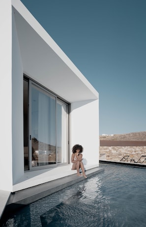A modern house with a large glass sliding door, a swimming pool, and a view of the desert. - Pnoes Tinos  (Tinos)