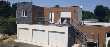 A modern two-story house with a balcony, a garage, and a staircase.