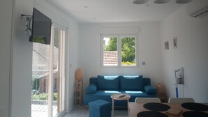 Una sala de estar moderna con un sofá azul, una mesita redonda y un comedor con una mesa de madera y sillas.