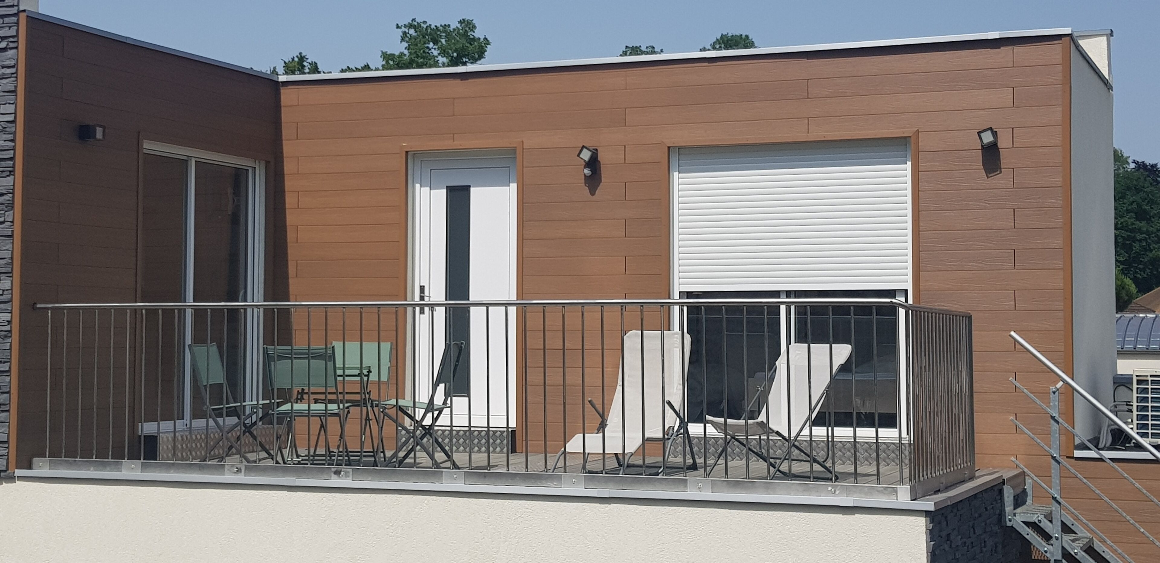 Un bâtiment doté d’un balcon, d’une porte de garage et d’une porte d’entrée.